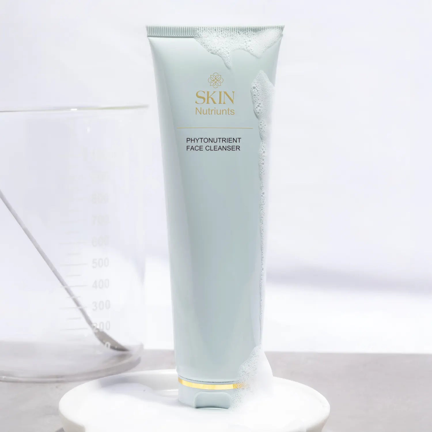 Tube of Skin Nutriunts Phytonutrient Face Cleanser on a white background with a beaker to the left side