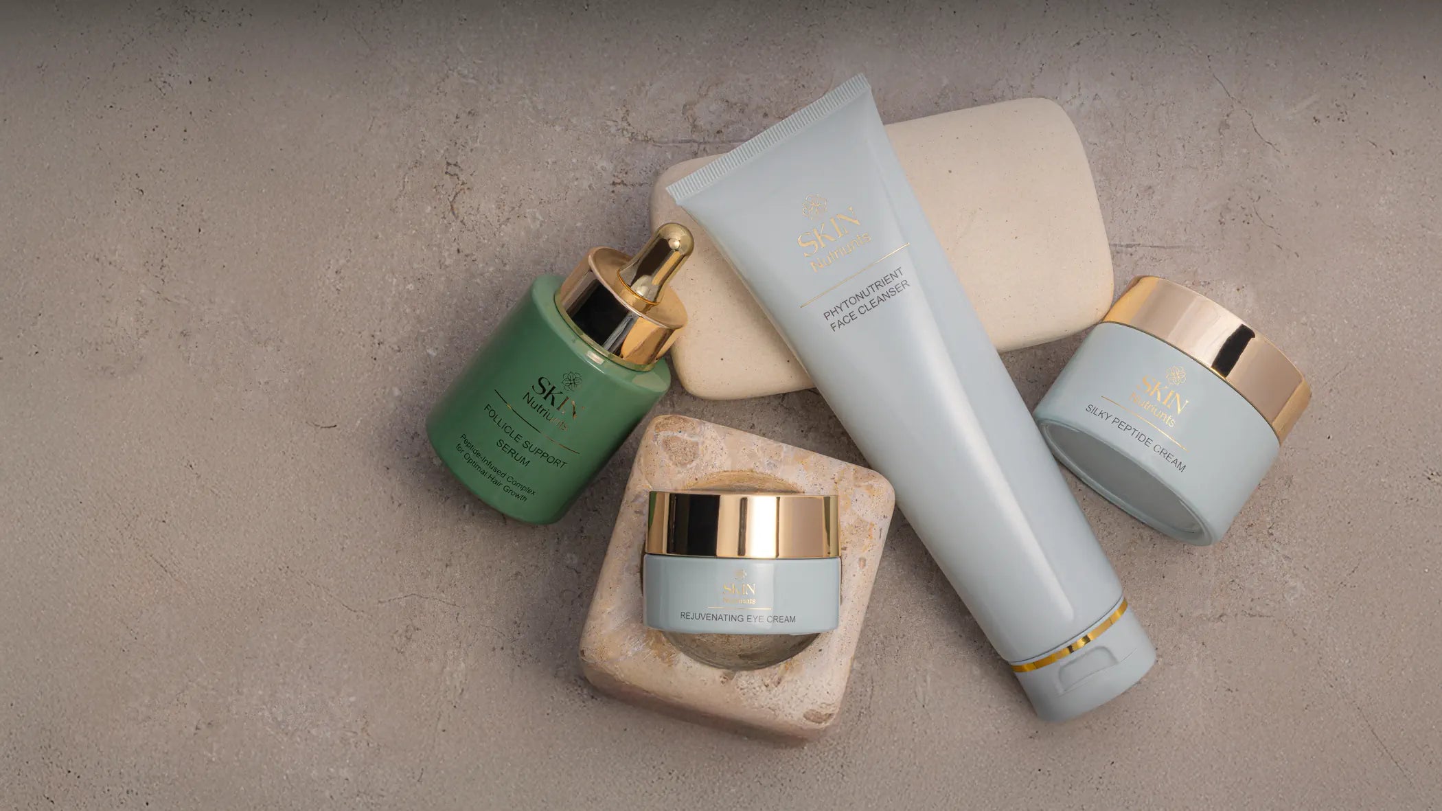 Set of Skin Nutriunts' skincare products on a textured sand stone surface